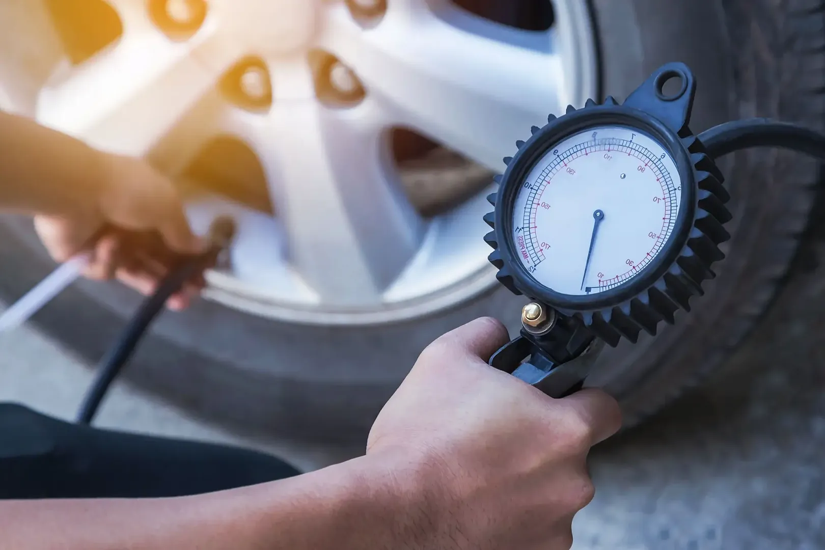 A person measuring tire pressure with a gauge.
