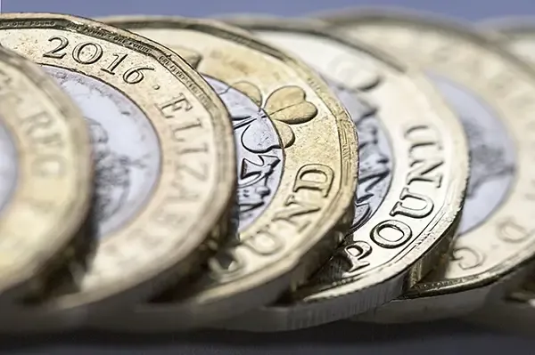 A close-up of British pound coins, showcasing their intricate design and varying denominations.