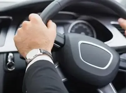 A man driving a car with both hands on the steering wheel.