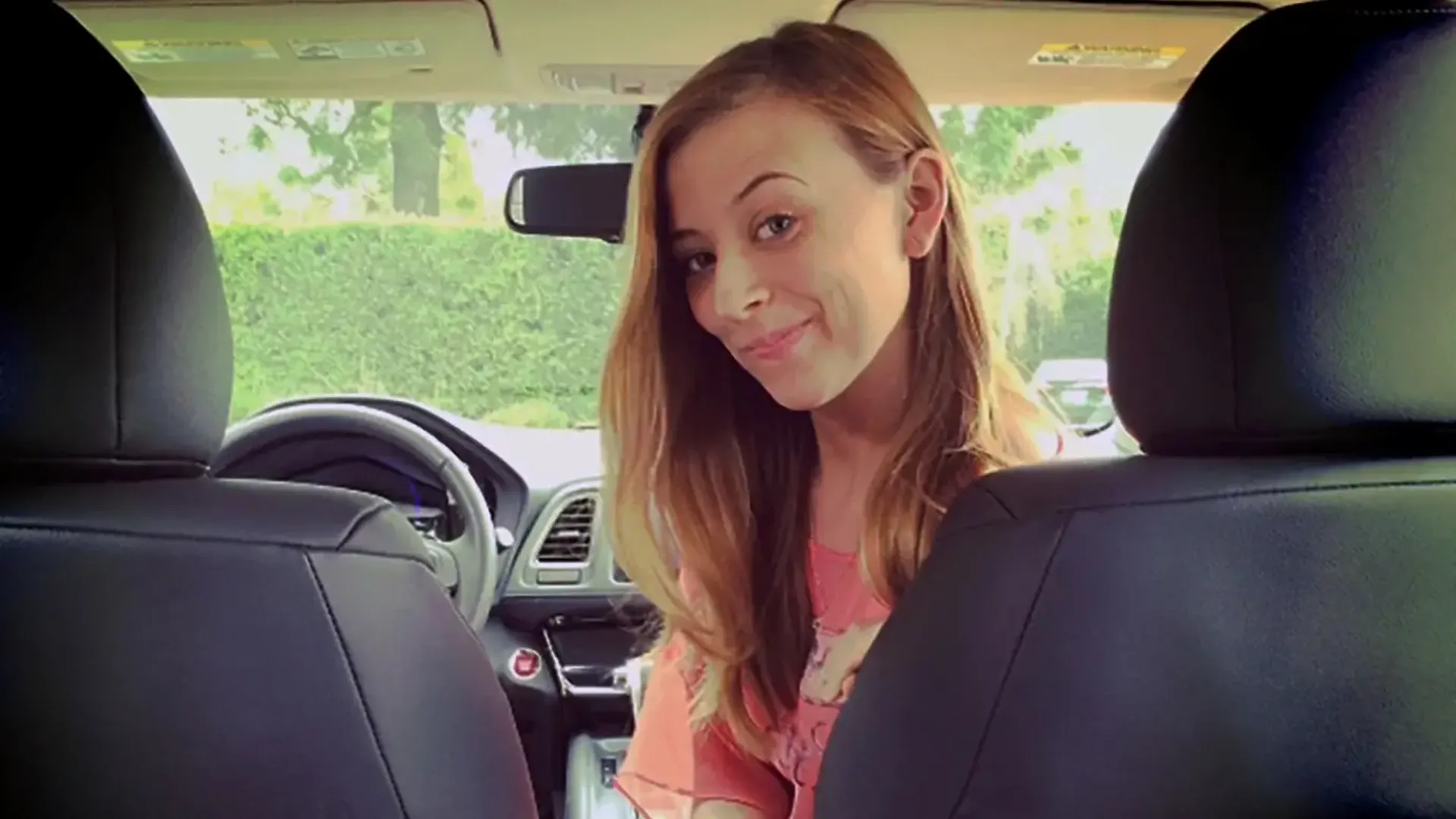 young woman sitting in the passenger seat of a car smiling back.