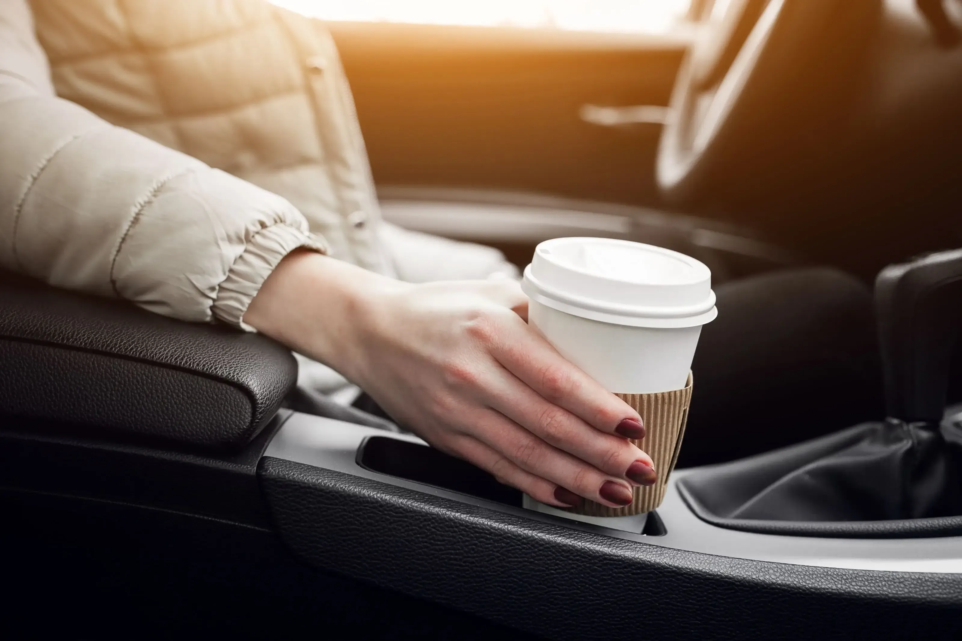 A woman enjoying a cup of coffee while sitting in a car.