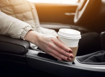 A woman enjoying a cup of coffee while sitting in a car.