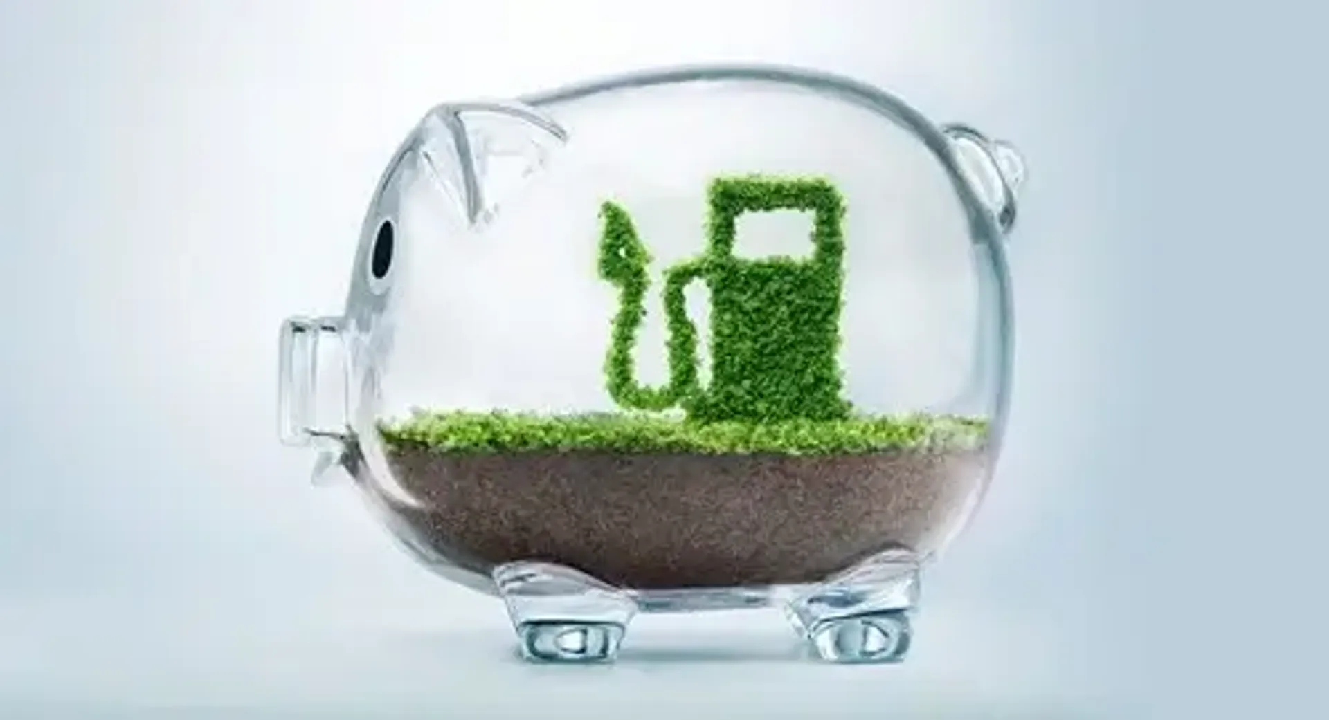 Green grass in a glass piggy bank with a fuel pump - a sustainable investment for a greener future.