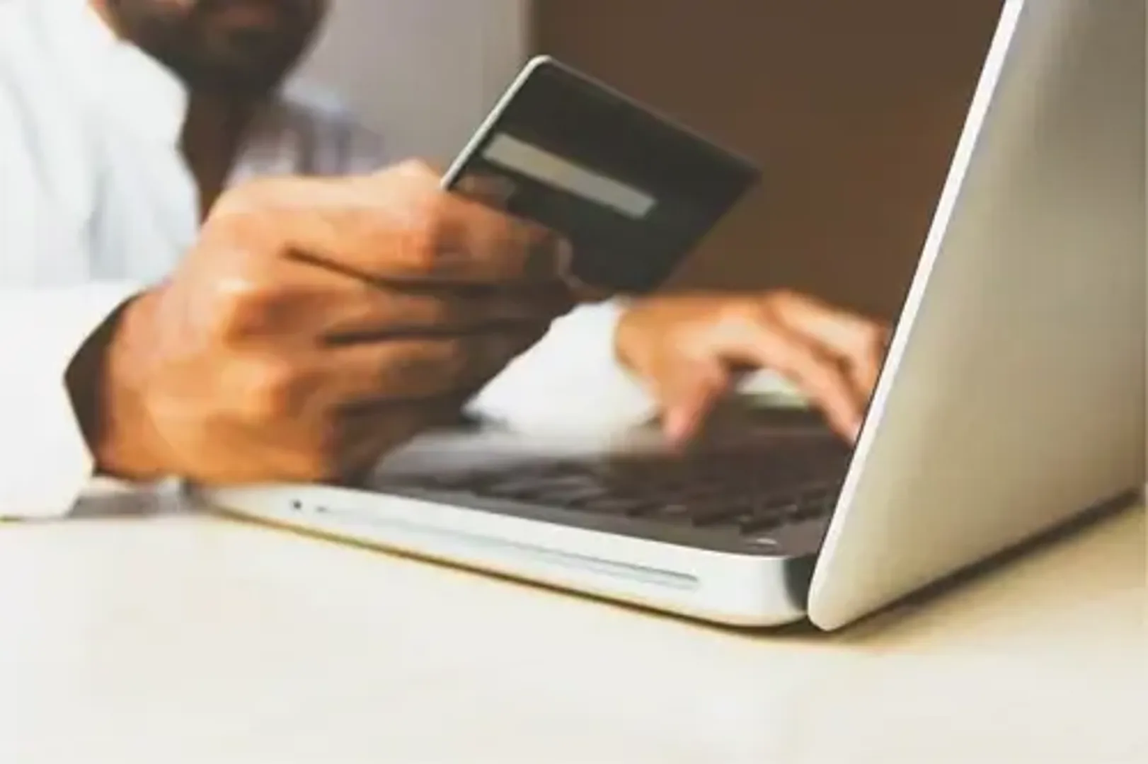 A man making an online purchase using a credit card on his laptop.