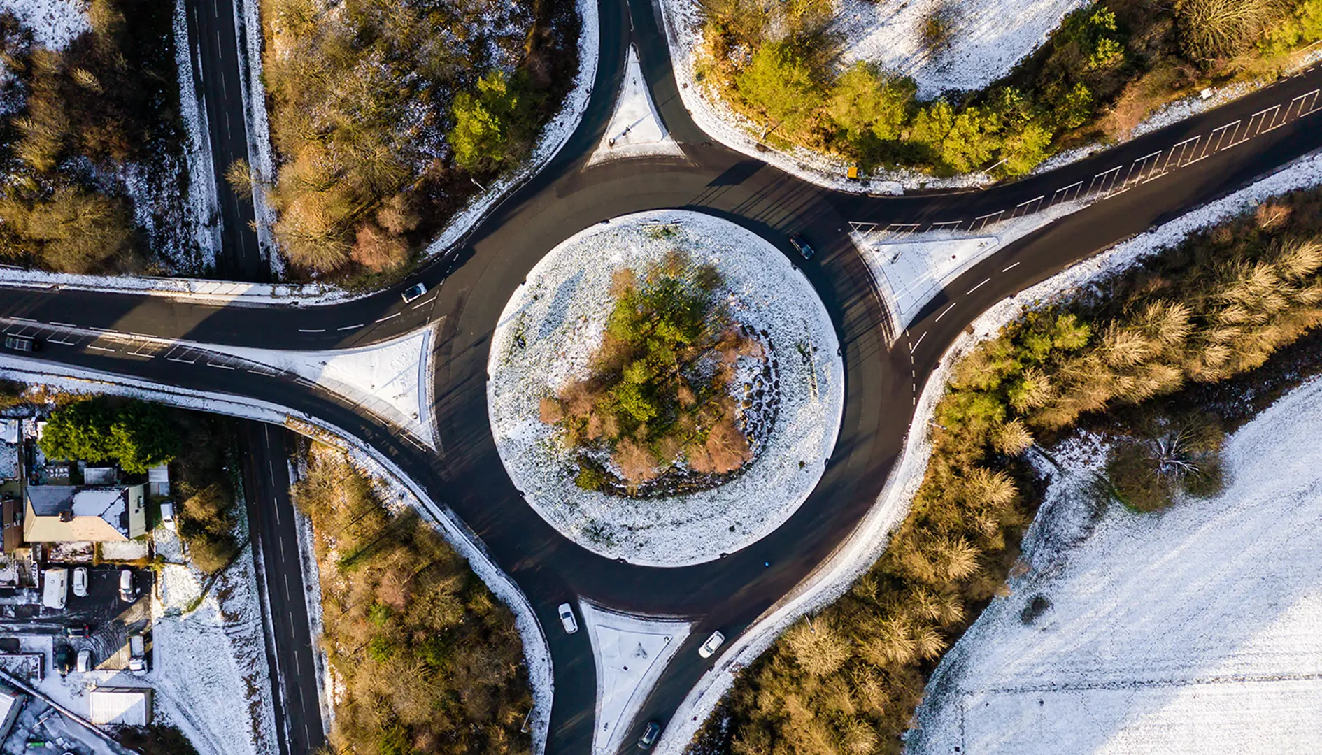 Aerial view of highway and roundabout in winter covered in snow.