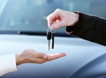 A person handing over a car key to another person.