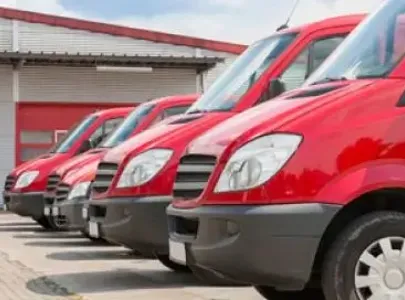 A lineup of red delivery trucks parked in front of a building.