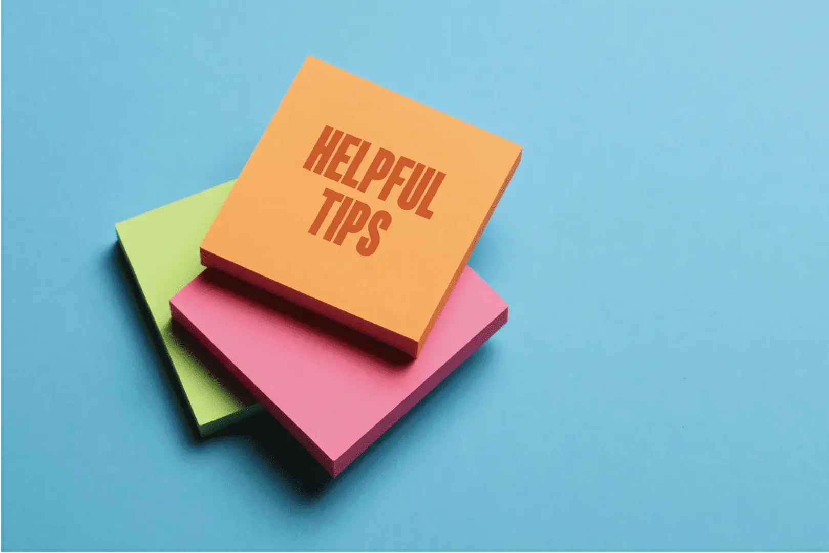 A pile of post it note pads, the top pad says 'helpful tips'