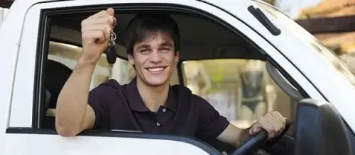 A young man with a cheerful expression driving a truck, radiating happiness and confidence.