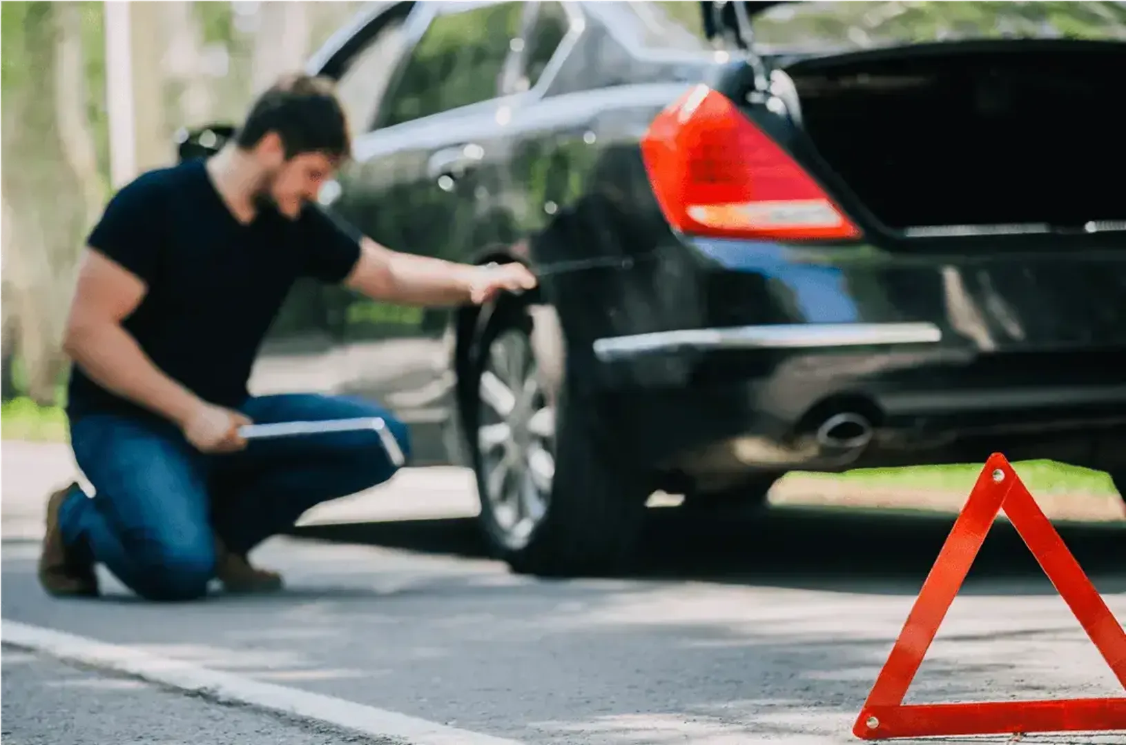 Man checking tyre with safety triangle out