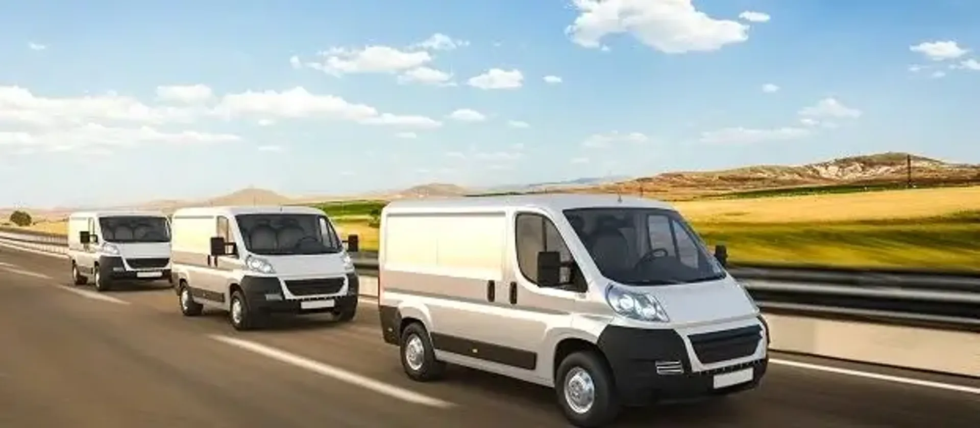 Three white delivery vans driving on the highway.