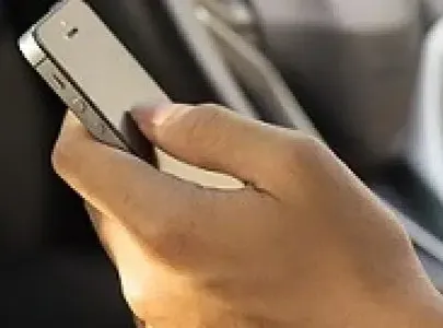 A person holding a cell phone whilst sitting in a car.