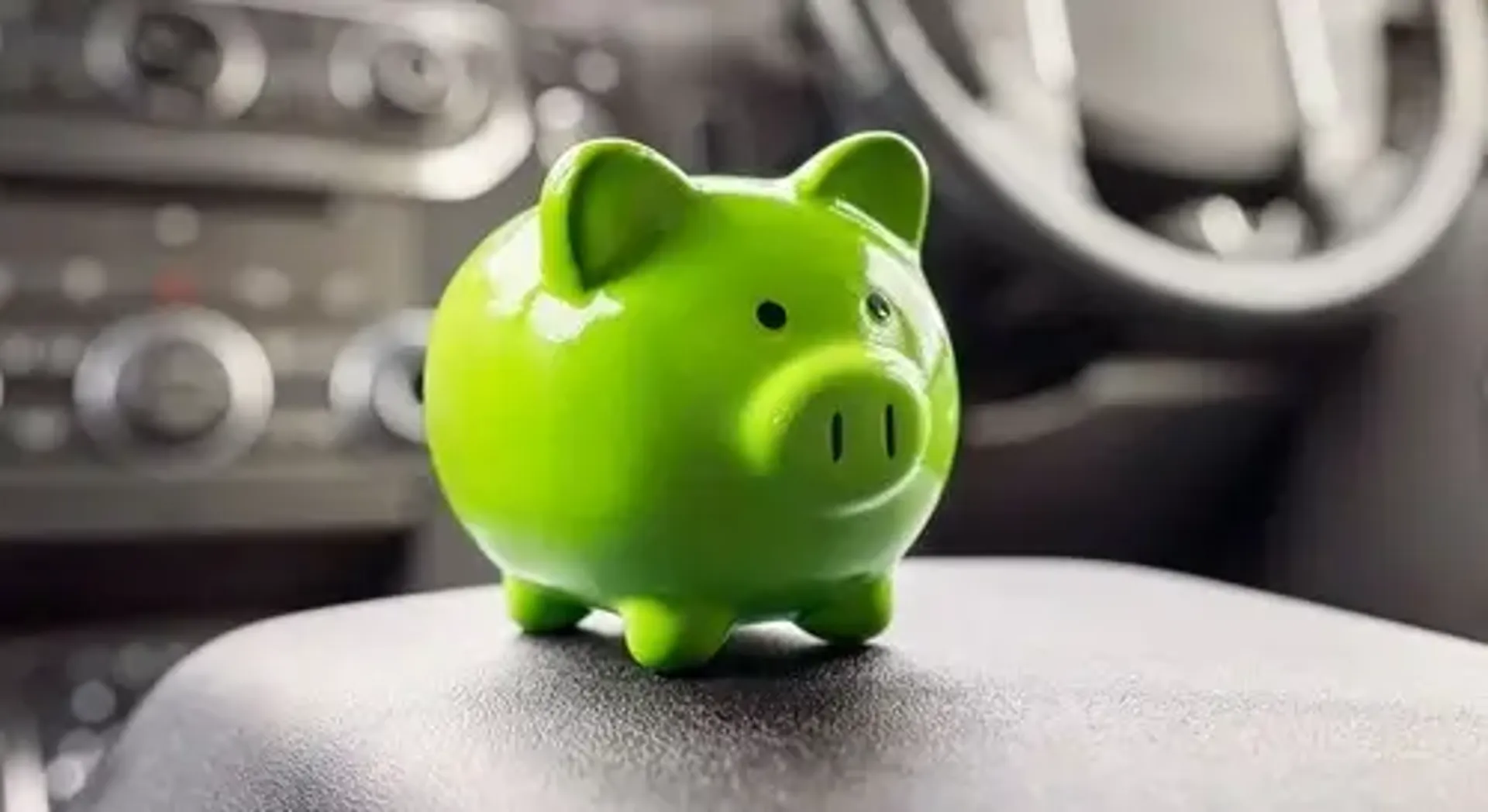 A green piggy bank on a car's dashboard, symbolizing savings and financial planning.